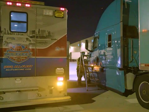All Fleet Inc service truck parked beside a teal semi-truck while a technician works on it in a lit yard at night